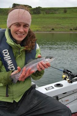 A young female angler holds up a rainbow trout